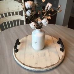 a white vase filled with flowers on top of a wooden table