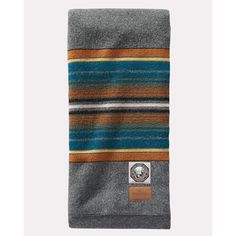 a grey and blue striped blanket with a leather patch on the bottom, in front of a white background