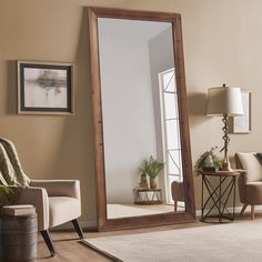 a large mirror sitting on top of a wooden floor next to a chair and table