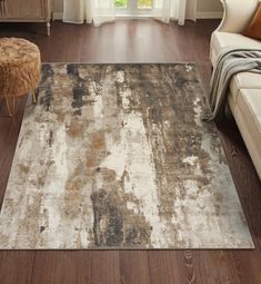 a living room area with a couch, chair and large rug on the hardwood floor