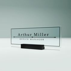 a glass sign sitting on top of a black stand in front of a white wall