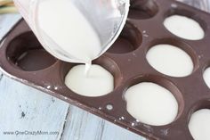 someone pouring milk into a chocolate muffin pan