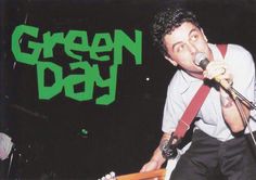 a man holding a guitar and singing into a microphone with the words green day on it