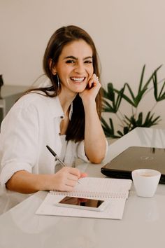 a woman sitting at a table with a notebook and pen