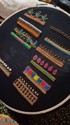 a black table topped with lots of different types of bracelets and brooches