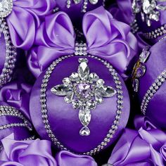 purple and silver ornaments with crystal cross on them are surrounded by satin flowers in the center