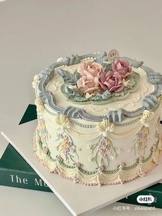 there is a decorated cake on top of the book and it has flowers in the middle