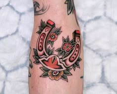 a tattoo on the leg of a person with flowers and an umbrella in the background