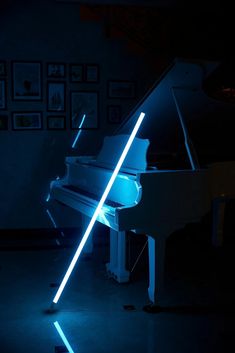 a white piano in a dark room with blue light coming from the top and side