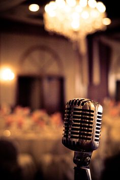 an old fashioned microphone in front of a chandelier at a banquet table with tables and chairs