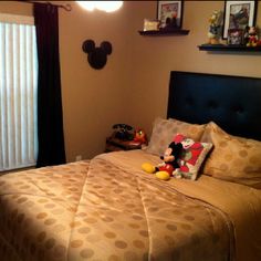 a mickey mouse stuffed animal sitting on top of a bed in a bedroom next to a window