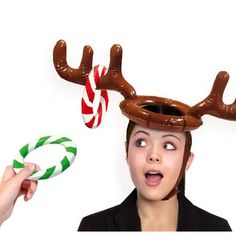 a woman wearing reindeer antlers and holding candy canes in front of her head