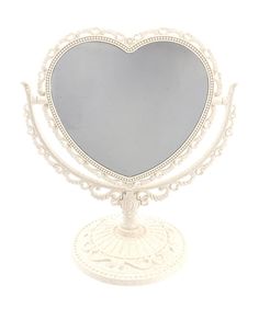 a white heart shaped mirror sitting on top of a stand