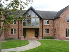 a large brick house with lots of windows on the front and side of it, surrounded by lush green grass