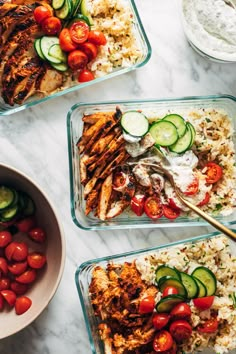 four glass containers filled with food on top of a white marble counter topped with cucumbers and tomatoes