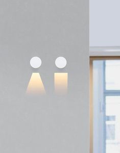 two lights that are on the side of a wall in front of a large window