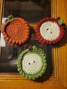 three crocheted apples sitting on top of a wooden table next to a mirror