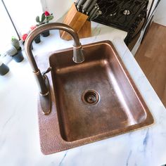 a kitchen sink with a faucet in the middle and marble counter top next to it