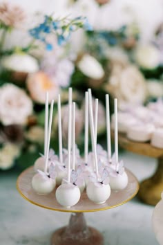 cake pops are arranged on a plate with flowers in the background