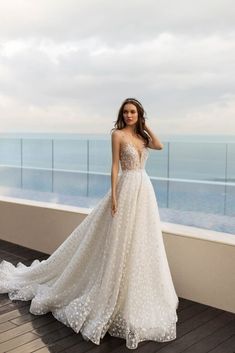 a woman in a wedding dress standing on a balcony with the ocean in the background