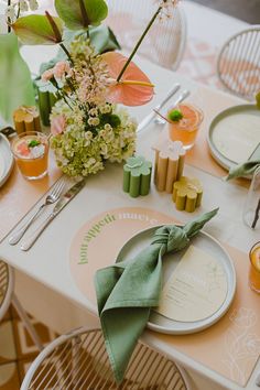 the table is set with plates, napkins and flowers