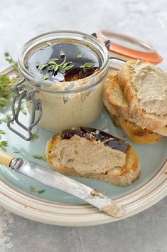 two pieces of bread sit on a plate next to a jar of peanut butter and jelly