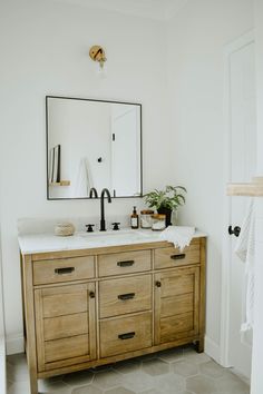 a bathroom vanity with two sinks and a large mirror above it, along with a potted plant