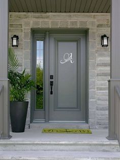 a gray front door with two planters on either side