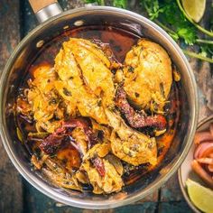 a pan filled with chicken and vegetables on top of a wooden table next to other foods