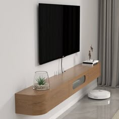 a flat screen tv mounted to the side of a wall next to a wooden shelf