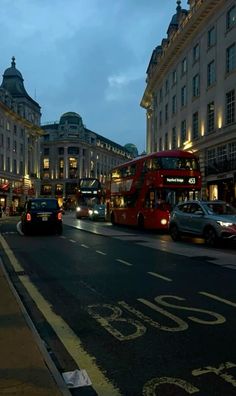 two red double decker buses driving down a city street