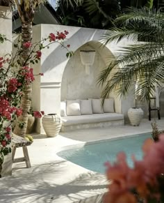 an outdoor living area with couches and flowers in the foreground, next to a swimming pool