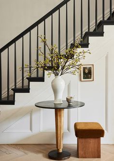 there is a vase with flowers on the table next to the stair case and bench