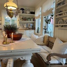 a table with two candles on it in a room filled with white furniture and decor