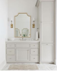 a white bathroom with two sinks and a large mirror over it's vanity area