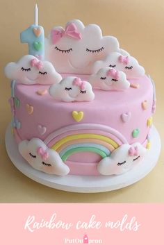 a pink cake with white clouds and rainbows