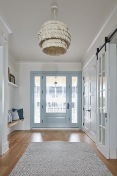 an empty hallway with blue doors and white trim on the front door, and a light fixture hanging from the ceiling