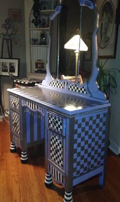 a blue vanity with checkered drawers and a mirror on it's side, in a living room