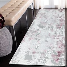 a white and red rug in a living room next to a bench with flowers on it