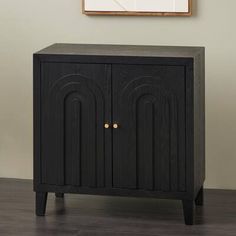 a black cabinet sitting in front of a wall with a framed painting on it's side