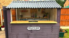 an outdoor bar made out of wood with a metal roof and sign that says milli's bar