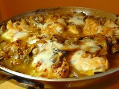 a pan filled with chicken and mushrooms covered in cheese