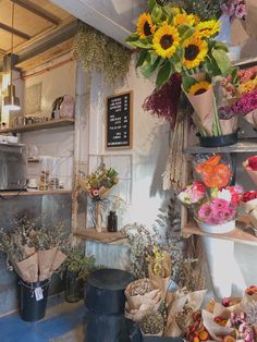 a flower shop with sunflowers and other flowers in the window, along with various types of dried flowers