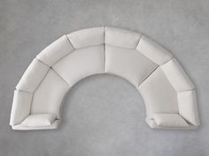 a white couch sitting on top of a gray floor next to a wall with an arch shaped cushion