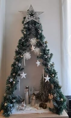 a small christmas tree with white stars and other decorations on it's sides in front of a window