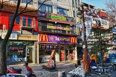 an image of a city street scene with stores and motorcycles parked on the side walk