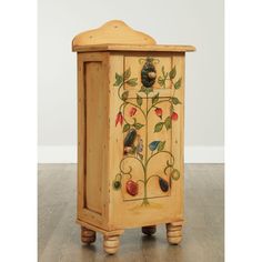 a wooden cabinet with birds and flowers painted on the front, sitting on top of a hard wood floor