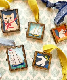 four framed pictures with cats and sailboats are hanging on a wall next to ribbons