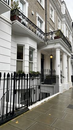 a white building with black iron railings and balconies on the side walk