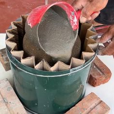 a man is working with cement in a bucket on the table next to some bricks